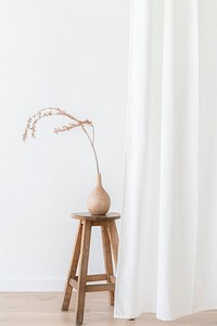 Dry Forsythia branch in a wooden vase on a stool by a white curtain