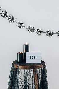 Boo on a letter board placed on the table with lighted candles 
