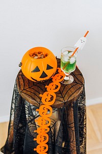 Halloween drink and a pumpkin basket filled with sugar candies on a table