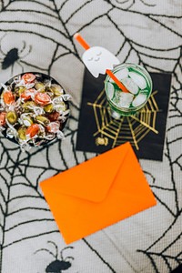 Orange envelope by a drink and a bowl of candies at a Halloween party 