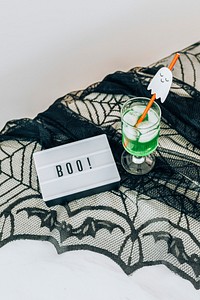 Boo inscription on a white letter board placed on a black lace tablecloth 