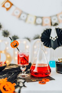 Halloween decoration with a red drink in a glass and a flask 
