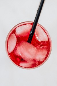 Red iced carbonated drink in a glass with a straw 