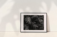 Botanical picture frame mockup psd leaning against the wall with plant shadow