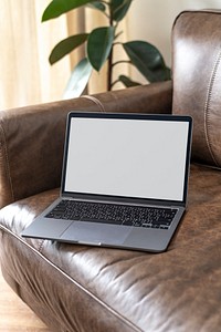 Laptop with empty screen on a leather couch