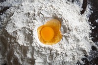 Raw egg yolk in flour on a wooden table