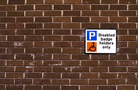 Disabled badge holders only sign on a brick wall