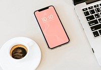 Phone mockup on white table with a laptop and a coffee cup
