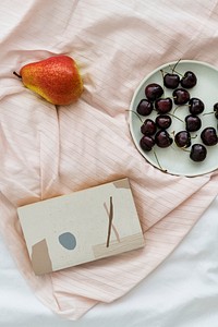 Fresh cherries and pear on a bed