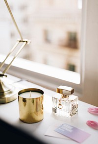 Perfume bottle and a candle by a window