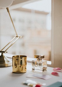 Perfume bottle and a candle by a window