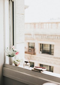 Flowers by a perfume bottle on a windowsill