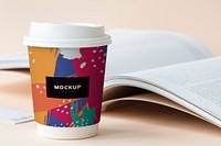 Takeaway coffee cup mockup on a table with an open book