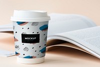Takeaway coffee cup mockup on a table with an open book