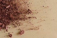 Broken brown bronzer powder on beige background