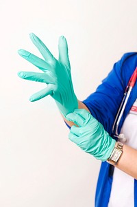 A healthcare provider donning a pair of green latex gloves in order to protect herself during her subsequent interaction her next patient.