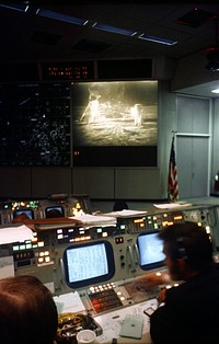 Interior view of the Mission Operations Control Room (MOCR) in the Mission Control Center (MCC). The television monitor shows astronauts Neil A. Armstrong and Edwin E. Aldrin Jr. on the surface of the moon. Original from NASA. Digitally enhanced by rawpixel.