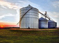 The set sets behind large, metal silos on a farm in Jackson County, Iowa. Original image from Carol M. Highsmith&rsquo;s America, Library of Congress collection. Digitally enhanced by rawpixel.