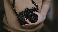 Woman holding a camera. Original public domain image from Wikimedia Commons