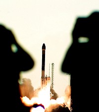 A Boeing Delta II rocket is framed between the ghostly silhouettes of two press photographers as it launches Deep Space 1 on its mission from Launch Complex 17A. Original from NASA. Digitally enhanced by rawpixel.