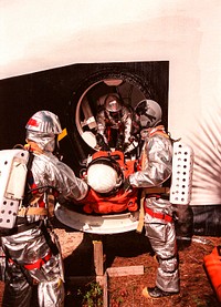 During a simulated rescue mission the KSC response team removes a Shuttle crew member from the mock orbiter. Original from NASA . Digitally enhanced by rawpixel.