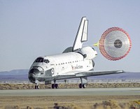 The space shuttle Atlantis lands with its drag chute deployed on runway 22 at Edwards, California. Original from NASA. Digitally enhanced by rawpixel.