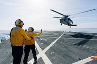 On the top deck of the USS San Diego, U.S. Navy personnel monitor a helicopter landing after an Orion underway recovery test. Original from NASA . Digitally enhanced by rawpixel.