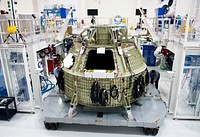 Technicians prepare to fit a special fixture around an Orion capsule inside the high bay of the Operations &amp; Checkout Building at NASA&#39;s Kennedy Space Center in Florida. Original from NASA. Digitally enhanced by rawpixel.