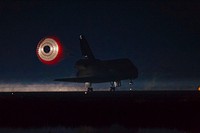 At the Shuttle Landing Facility at NASA's Kennedy Space Center in Florida, the drag chute trailing space shuttle Atlantis is illuminated by the xenon lights on Runway 15 as the shuttle lands for the final time. Original from NASA. Digitally enhanced by rawpixel.
