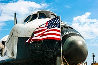 An American flag flaps proudly in the wind in front of space shuttle Atlantis on the Shuttle Landing Facility's Runway 15 at NASA's Kennedy Space Center in Florida. Original from NASA. Digitally enhanced by rawpixel.