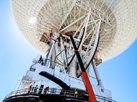 Under the unflinching summer sun, workers at NASA&#39;s Deep Space Network complex in Goldstone, Calif., use a crane to lift a runner segment that is part of major surgery on a giant, 70-meter-wide antenna. Original from NASA . Digitally enhanced by rawpixel.