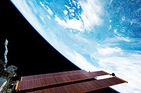 International Space Station solar array panels and a blue and white part of Earth are featured in this image photographed by an STS-134 crew member onboard the station during flight day six activities, 21 May 2011. Original from NASA. Digitally enhanced by rawpixel.