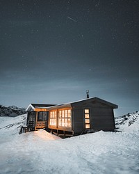 Lights from a wooden cabin in the remote wilderness of Greenland
