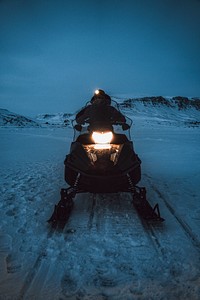 Man riding a snowmobile in the evening