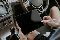 Hand holding stylus pen on a tablet screen in a car