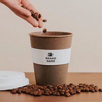 Hand pouring coffee beans into a cork coffee cup mockup