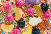 Flatlay of assorted jelly fruits and sprinkles textured background