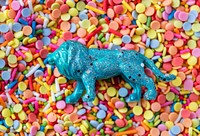 Close up of a blue lion figurine toy on a bed of sweet candy sprinkles