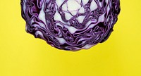 Closeup of purple round cabbage cut in half in a yellow background
