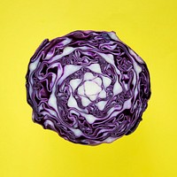 Closeup of purple round cabbage cut in half in a yellow background
