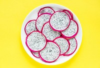 Closeup of a plate of dragon fruit slices on yellow background