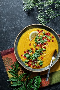 Fresh pumpkin soup topped with parsley and pomegranate seeds