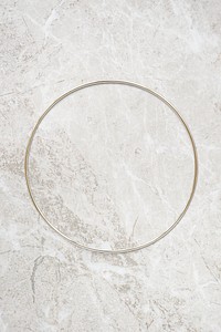 Round gold frame on beige marble background