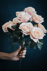 Hand holding a bouquet of light orange roses