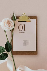 Pastel pink calendar on a cork clipboard with light pink rose