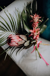 A bouquet of king protea and red pineapples on a sofa<br />