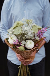 Man holding a bouquet of white dahlia flowers