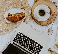 Plate of croissant served with a cup of coffee next to a laptop