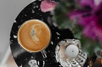 Aerial view of a coffee cup by a vase on a black table