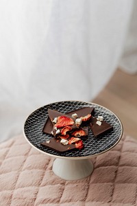 Dark chocolate brittle on a plate on top of a pink velvet cushion